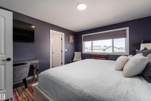 Spacious room featuring a large window, dark accent wall, ceiling-mounted light fixture, and white trim - 1450 Darby Green, Edmonton, AB - Indoor Photo Showing Bedroom
