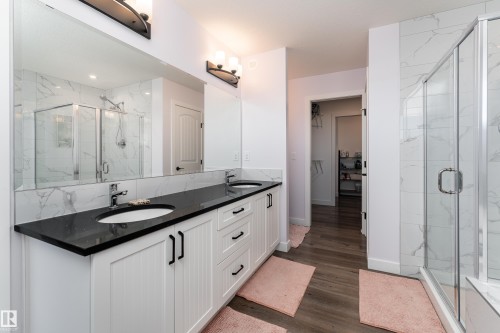 Double vanity with black countertops and integrated sinks - 1450 Darby Green, Edmonton, AB - Indoor Photo Showing Bathroom