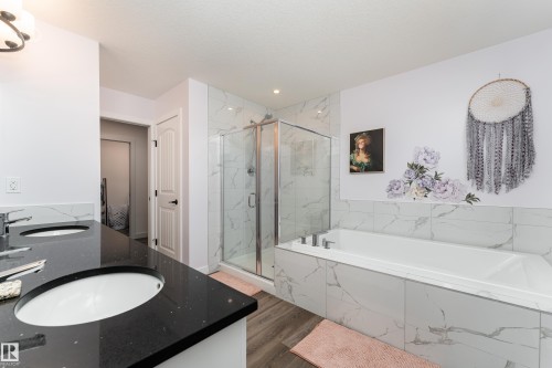 Dual vanity with black speckled countertops and undermount sinks - 1450 Darby Green, Edmonton, AB - Indoor Photo Showing Bathroom