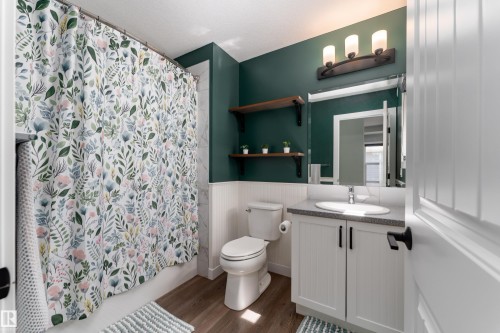 Bathroom featuring a white vanity with panel-front cabinetry, a single basin sink, and a gray countertop - 1450 Darby Green, Edmonton, AB - Indoor Photo Showing Bathroom