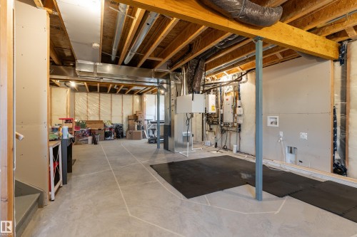 Unfinished basement offering concrete flooring, exposed wood joists and subfloor, structural support beams, and visible utility connections - 1450 Darby Green, Edmonton, AB - Indoor Photo Showing Basement