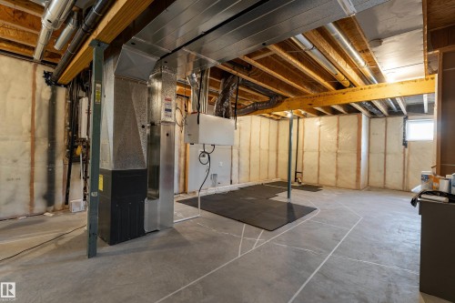 Unfinished basement featuring exposed wood ceiling joists and support beams, concrete flooring, insulated perimeter walls, and visible utility infrastructure including ductwork and piping - 1450 Darby Green, Edmonton, AB - Indoor Photo Showing Basement