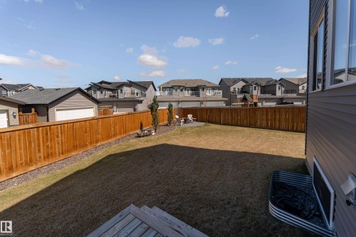 Expansive backyard featuring a manicured lawn, a full-height wood fence, a gravel perimeter, and a circular paved patio - 1450 Darby Green, Edmonton, AB - Outdoor