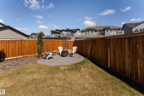 Expansive backyard featuring a manicured lawn, a gravel patio area, and a fire pit - 1450 Darby Green, Edmonton, AB - Outdoor