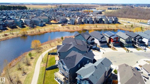 Expansive community featuring numerous single-family residences, a tranquil pond, and a paved walking path - 1450 Darby Green, Edmonton, AB - Outdoor With Body Of Water With View