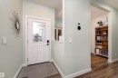 Entryway featuring a white paneled door with a clear glass insert, a black digital lockset, wood-finish flooring, light-colored wall paint, and white baseboards - 1450 Darby Green, Edmonton, AB  - Indoor Photo Showing Other Room 