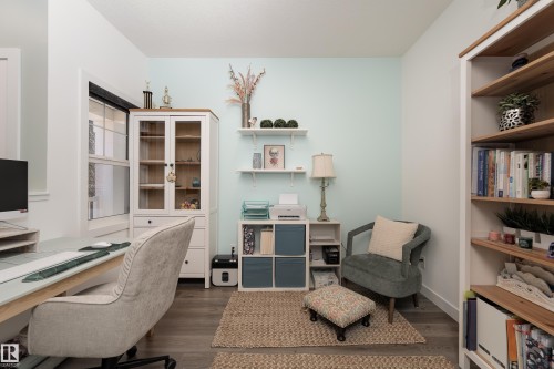 Dedicated room featuring wood-finish flooring, a built-in wall unit with wood shelving, and a large window providing natural light - 1450 Darby Green, Edmonton, AB - Indoor Photo Showing Office