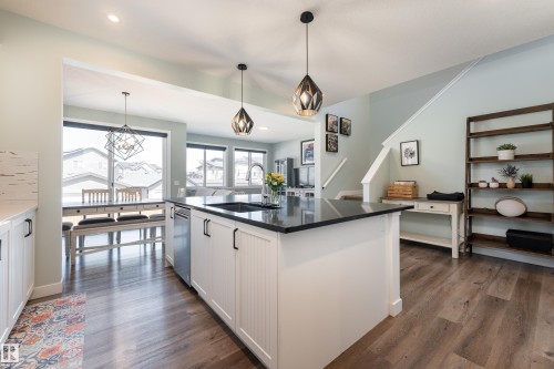 Kitchen featuring a large island with black countertop, stainless steel sink, and dishwasher - 1450 Darby Green, Edmonton, AB - Indoor Photo Showing Kitchen