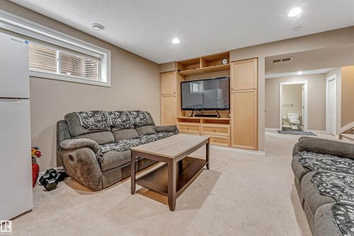 Finished lower level featuring a built-in entertainment center with wood-finish cabinetry, recessed lighting, and light-colored carpeting - 3236 26 Avenue, Edmonton, AB - Indoor Photo Showing Other Room