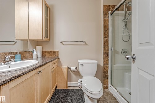 Full bathroom featuring a single vanity with stone-finish countertop, wood-finish cabinetry, and an enclosed shower with a sliding glass door - 3236 26 Avenue, Edmonton, AB - Indoor Photo Showing Bathroom