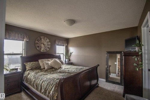 Carpeted room with neutral wall tones and two windows - 5121 52 Ave, St. Paul Town, AB - Indoor Photo Showing Bedroom