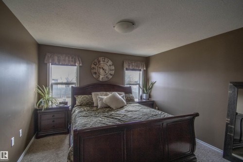 Carpeted bedroom featuring two windows with valances and a flush-mount ceiling light fixture - 5121 52 Ave, St. Paul Town, AB - Indoor Photo Showing Bedroom