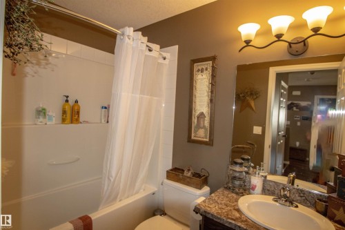 Bathroom featuring a full tub and shower combination, vanity with an integrated sink, polished chrome faucet, and a wall-mounted light fixture with three sconces - 5121 52 Ave, St. Paul Town, AB - Indoor Photo Showing Bathroom