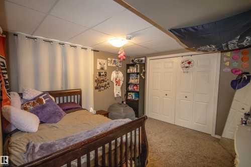 Room featuring carpeted flooring, a ceiling-mounted light fixture, white bi-fold closet doors, and recessed drop ceiling tiles - 5121 52 Ave, St. Paul Town, AB - Indoor Photo Showing Bedroom