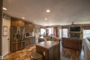 Open-concept kitchen featuring wood-finish flooring, recessed lighting, a stainless steel refrigerator, stone-look countertops, and an integrated kitchen island with a double basin sink - 5121 52 Ave, St. Paul Town, AB  - Indoor Photo Showing Kitchen 