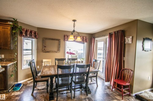 Dining area featuring wood-finish flooring, a pendant light fixture, and two windows - 5121 52 Ave, St. Paul Town, AB - Indoor Photo Showing Dining Room