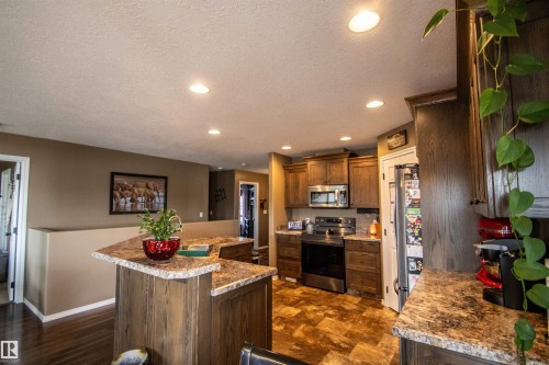 Kitchen featuring wood-finish cabinetry, stainless steel appliances, speckled countertops, recessed lighting, and wood-finish flooring - 5121 52 Ave, St. Paul Town, AB - Indoor Photo Showing Kitchen