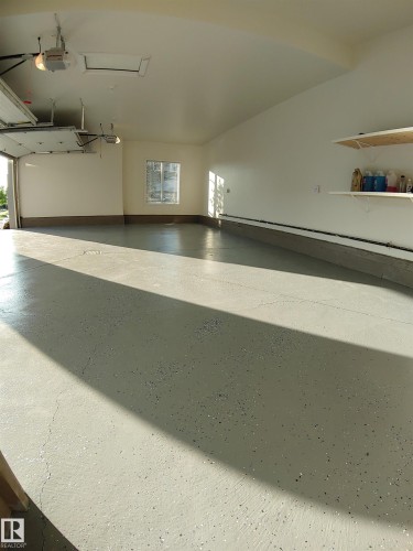 Spacious garage featuring a finished epoxy floor, white painted walls, and a window for natural light - 4125 Kennedy Green, Edmonton, AB - Indoor Photo Showing Other Room