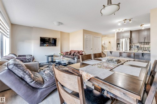 Open-concept living space featuring wood-finish flooring, a dining area with an overhead light fixture, and a kitchen with stainless steel appliances and dark cabinetry - 1715 27 Street, Edmonton, AB - Indoor