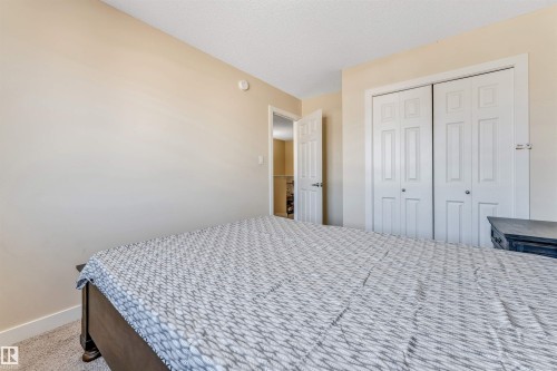 Bedroom featuring light-colored walls, carpet flooring, a bifold closet, and a white paneled door - 1715 27 Street, Edmonton, AB - Indoor Photo Showing Bedroom