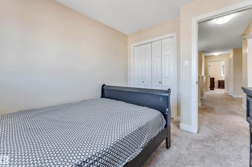 Recessed closet with bi-fold doors, neutral wall tones, and textured carpeting - 1715 27 Street, Edmonton, AB - Indoor Photo Showing Bedroom