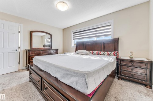 Carpeted room featuring a ceiling-mounted light fixture, a window with horizontal blinds, and a white paneled door - 1715 27 Street, Edmonton, AB - Indoor Photo Showing Bedroom