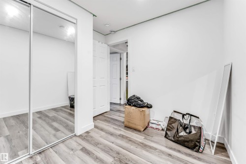 Room featuring wood-finish flooring, crisp white walls, and a closet with mirrored sliding doors - 1715 27 Street, Edmonton, AB - Indoor Photo Showing Other Room