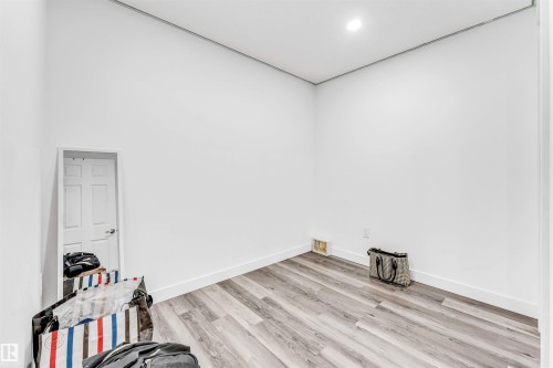 Room featuring wood-finish flooring, white walls, recessed ceiling lighting, and a white six-panel door - 1715 27 Street, Edmonton, AB - Indoor Photo Showing Other Room