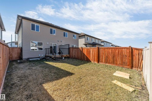 Expansive backyard featuring a brown stained wood fence, a ground-level deck with black railings, and siding on the exterior - 1715 27 Street, Edmonton, AB - Outdoor