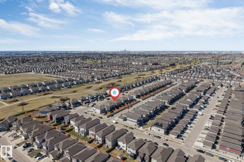 Aerial perspective showcasing a residential development with numerous single-family homes and townhomes, featuring a distant city skyline - 1715 27 Street, Edmonton, AB - Outdoor With View