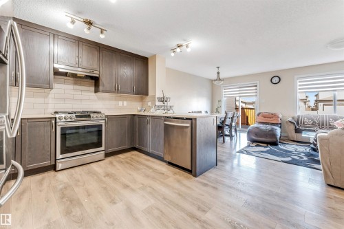 Kitchen featuring wood-finish flooring, dark wood cabinetry, stainless steel appliances, and a tiled backsplash - 1715 27 Street, Edmonton, AB - Indoor Photo Showing Kitchen With Upgraded Kitchen