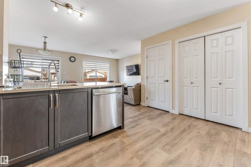 Kitchen island with a built-in stainless steel dishwasher, an undermount sink, and light-toned countertops - 1715 27 Street, Edmonton, AB - Indoor Photo Showing Kitchen