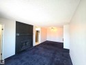Living area featuring a black brick fireplace with a mantel, dark carpet flooring, and white walls - 304 34 Alpine Place, St. Albert, AB  - Indoor With Fireplace 