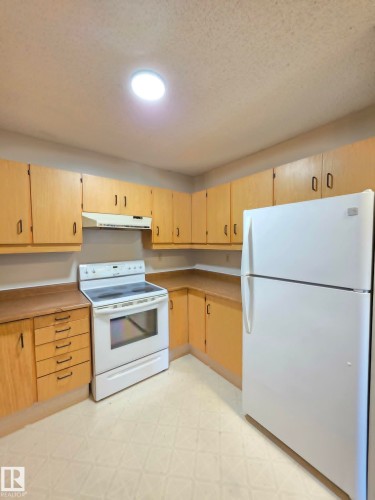 Kitchen featuring light wood-finish cabinetry, white appliances, and a recessed ceiling light - 304 34 Alpine Place, St. Albert, AB - Indoor Photo Showing Kitchen
