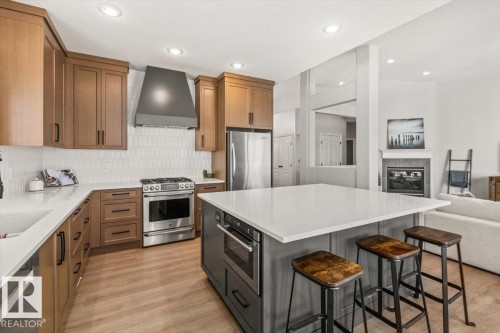 Gourmet kitchen featuring a substantial island with seating, stainless steel appliances, light wood-finish cabinetry, white countertops, and recessed lighting - 7719 166 Avenue, Edmonton, AB - Indoor Photo Showing Kitchen With Upgraded Kitchen