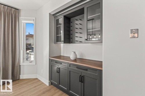 Built-in cabinetry featuring a wood-finish countertop, glass-front upper cabinets, and integrated wine storage - 7719 166 Avenue, Edmonton, AB - Indoor Photo Showing Other Room