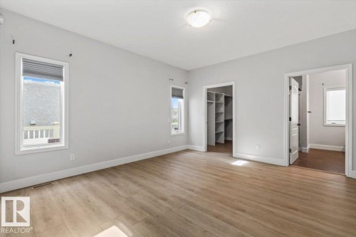 Spacious room featuring light wood-finish flooring, light gray walls, and white trim - 7719 166 Avenue, Edmonton, AB - Indoor Photo Showing Other Room