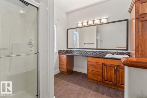 Bathroom featuring a glass-enclosed shower, a wide vanity with a single basin sink, a large framed mirror, and a mosaic tile backsplash - 7719 166 Avenue, Edmonton, AB - Indoor Photo Showing Bathroom