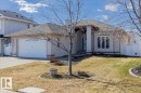 Stucco exterior residence featuring an attached garage, prominent front columns, a paved driveway, and a partially fenced yard - 7719 166 Avenue, Edmonton, AB  - Outdoor 