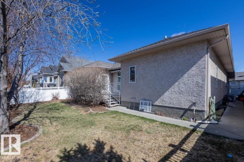Property exterior featuring stucco siding, a gravel roof, and multiple windows - 7719 166 Avenue, Edmonton, AB - Outdoor