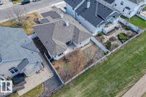 Rear exterior featuring a multi-level deck, a stone patio, and a manicured lawn - 7719 166 Avenue, Edmonton, AB - Outdoor
