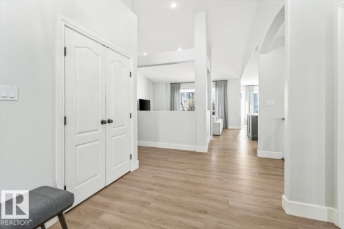 Hallway featuring wood-finish flooring, white baseboards, vaulted ceiling, recessed lighting, and arched doorway - 7719 166 Avenue, Edmonton, AB - Indoor Photo Showing Other Room