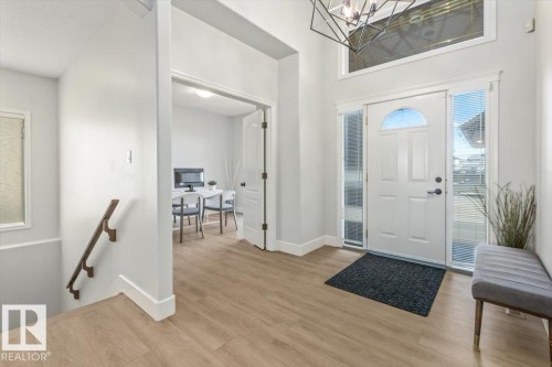 Foyer featuring wood-finish flooring, a white paneled entry door with an arched window, and sidelight windows - 7719 166 Avenue, Edmonton, AB - Indoor Photo Showing Other Room