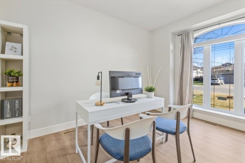 Bright room featuring a large arched window, wood-finish flooring, and white baseboards - 7719 166 Avenue, Edmonton, AB - Indoor Photo Showing Office