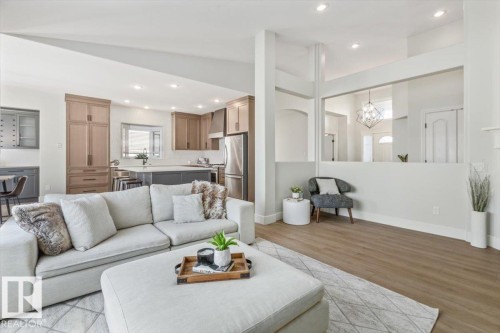 Open-concept living space featuring wood-finish flooring, recessed lighting, a kitchen with stainless steel appliances, and a central island with bar seating - 7719 166 Avenue, Edmonton, AB - Indoor Photo Showing Living Room