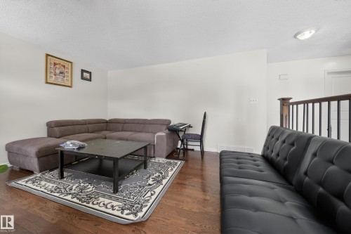 Living area featuring wood-finish flooring, white walls, and a textured ceiling - 8312 29 Ave Nw, Edmonton, AB - Indoor Photo Showing Living Room
