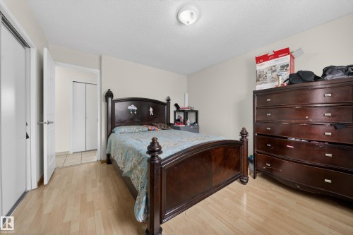 Bedroom featuring wood-finish flooring, neutral wall paint, and a white ceiling with a flush-mount light fixture - 8312 29 Ave Nw, Edmonton, AB - Indoor Photo Showing Bedroom