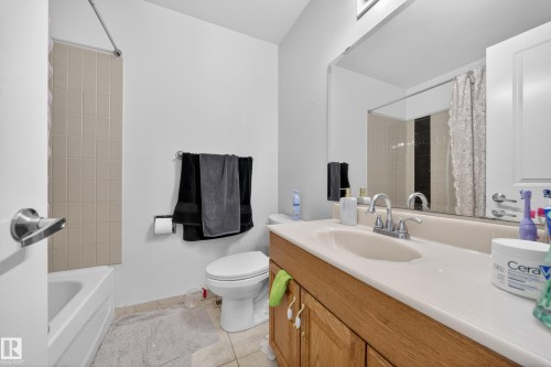 Bathroom with a light-toned vanity featuring a built-in sink, a large wall-mounted mirror, and a toilet - 8312 29 Ave Nw, Edmonton, AB - Indoor Photo Showing Bathroom
