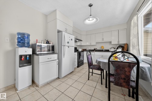 Kitchen featuring white cabinetry, light-toned tile flooring, and a large window - 8312 29 Ave Nw, Edmonton, AB - Indoor Photo Showing Other Room