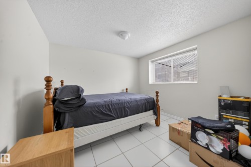 Bedroom featuring light-colored walls, white tile flooring, a horizontal window with blinds, and a white ceiling with a flush-mount light fixture - 8312 29 Ave Nw, Edmonton, AB - Indoor Photo Showing Bedroom